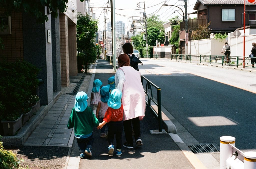 Must-sees in Tokyo met kinderen – Kitsune Travel Tokyo - Kinderen met begeleider in een straat in Tokyo