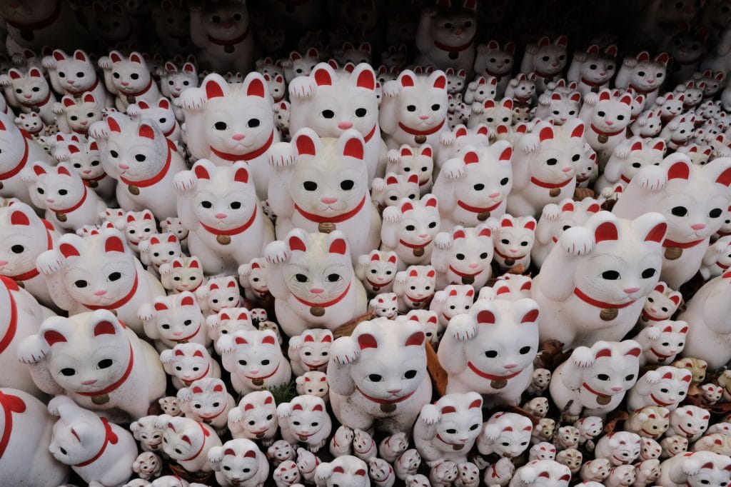 Japan met kinderen: 10 ervaringen die je niet mag missen op je rondreis – Kitsune Travel Een grote verzameling Maneki-neko beeldjes met opgeheven pootjes voor geluk.