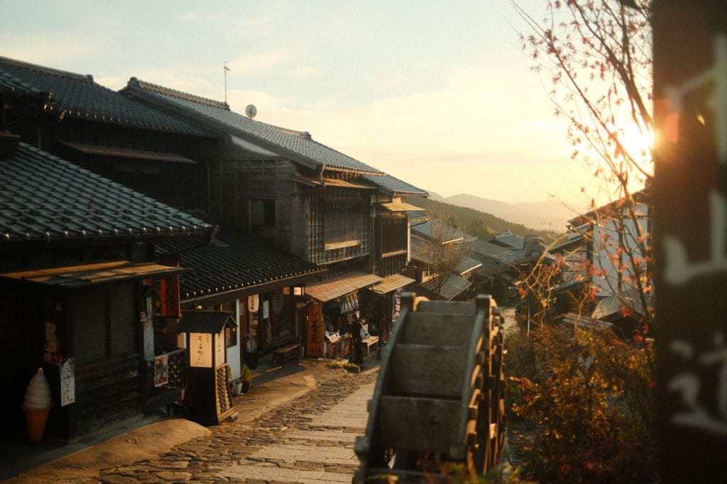Off the beaten path in Japan: 4 rustige alternatieven voor de drukste hotspots – Kitsune Travel Een vredige, traditionele Japanse straat, verlicht door de warme zonsondergang, met een prachtig uitzicht op historische architectuur.