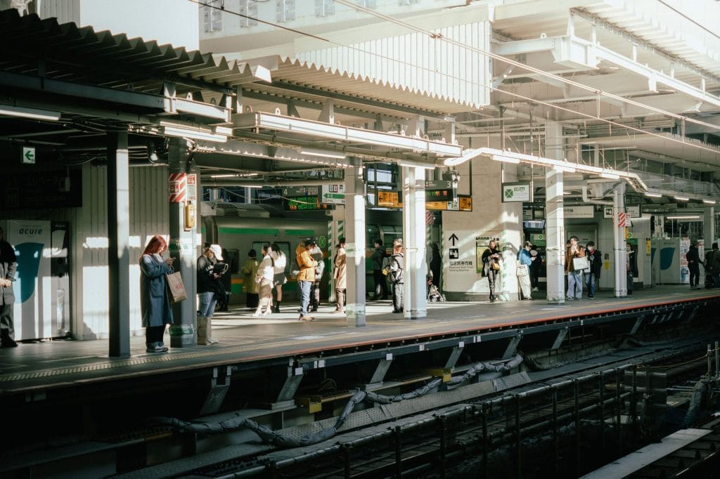 Rondreis door Japan: de beste route voor 1, 2 of 3 weken (met kinderen) – Kitsune Travel Mensen die overdag op een perron van een treinstation wachten, een momentopname van het stadsleven.