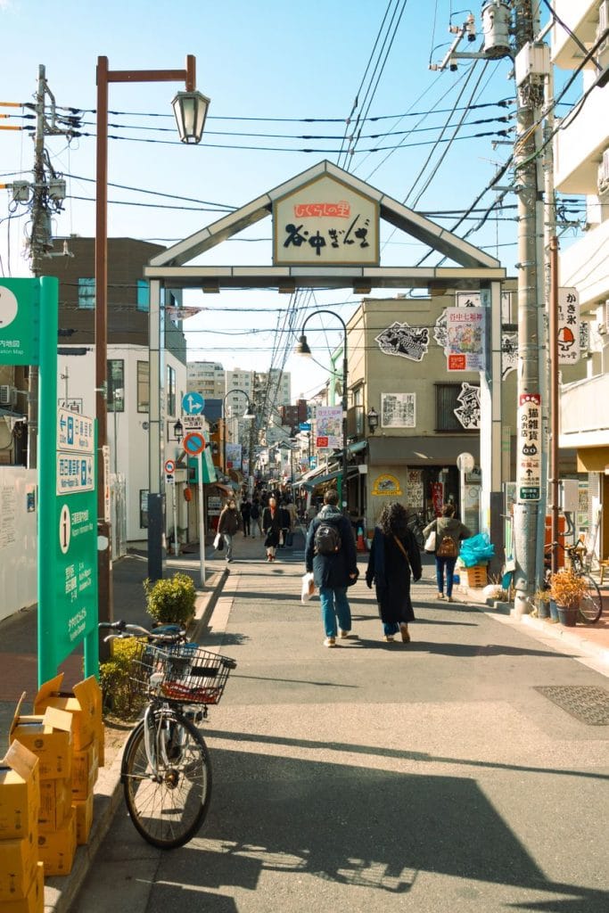 Off the beaten path in Japan: 4 rustige alternatieven voor de drukste hotspots – Kitsune Travel Een levendig straatbeeld in Yanaka Ginza, Tokio, dat de charme van lokale winkels en voetgangers vastlegt.