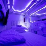Comfortabel bed met zachte kussens in een verlichte kamer van een creatief, futuristisch capsulehotel.