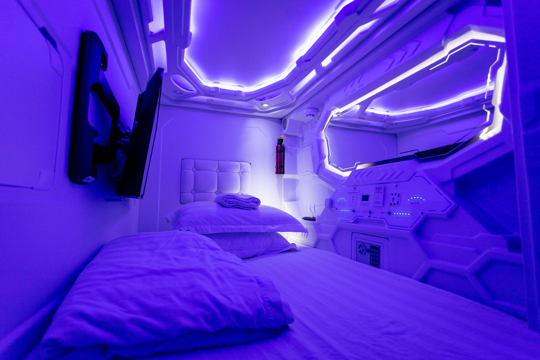 Goedkoop overnachten in Japan: van capsulehotel tot ryokan – Kitsune Travel Comfortabel bed met zachte kussens in een verlichte kamer van een creatief, futuristisch capsulehotel.