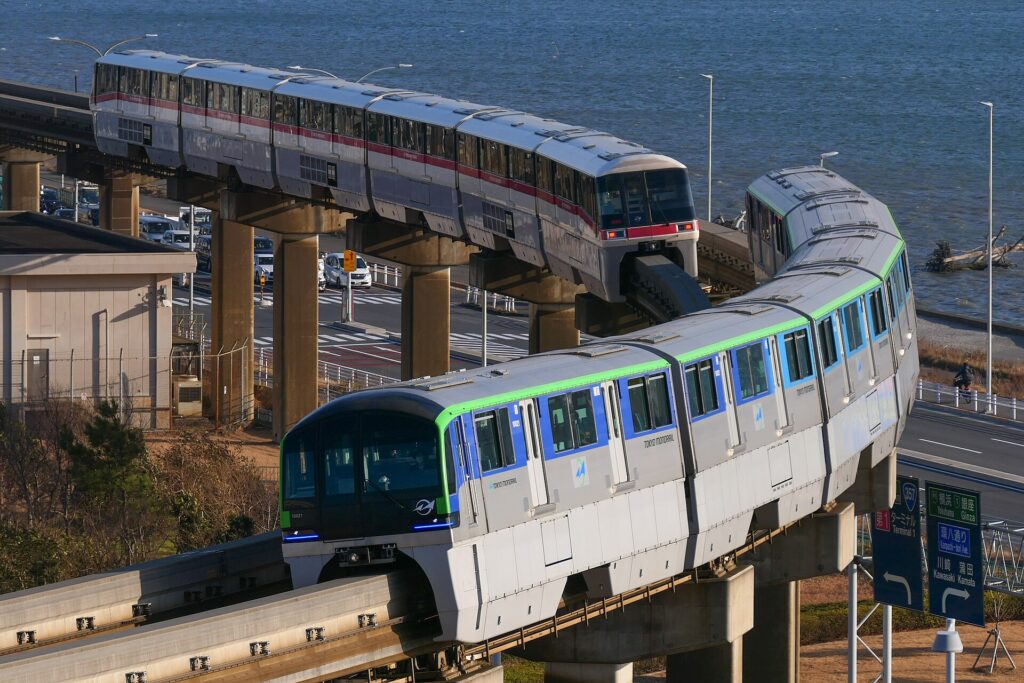 Openbaar vervoer in Tokyo: zo werkt het, van metro tot waterbus – Kitsune Travel Twee Tokyo Monorail-treinen op hoge pijlers langs het water