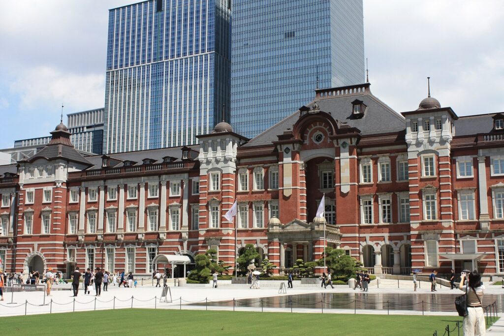 De rode baksteen van de Marunouchi-kant van Tokyo Station met wolkenkrabbers erachter